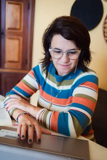 Melissa Teixeira em atendimento online, com fones de ouvido em frente ao notebook